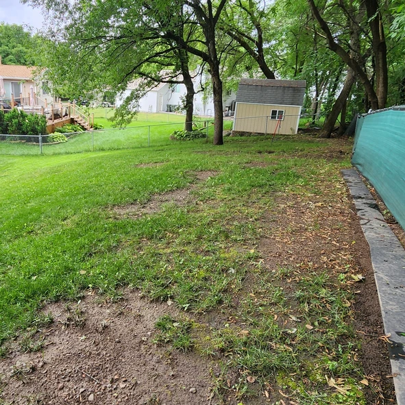 a yard with a fence and a house with just dirt and grass