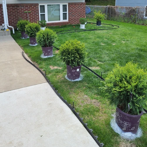 a house with yard displaying spray painted sections to display plant location, surrounded by uninstalled edging