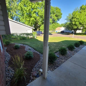 wide angle view from front door overlooking the front yard with completed landscaping of shrubs lining both house and walkway.