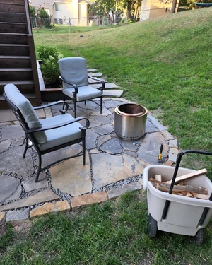 view of a backyard flagstone patio with a couple of chairs facing a fire pit