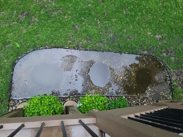 view of a garden bed being installed after a heavy rain, that has filled the plants holes with standing water.