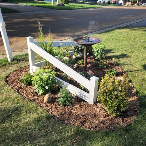 a small garden with a fountain in the middle of a yard