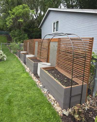 side view of raised garden beds filled with dirt and small plants beginning to sprout.